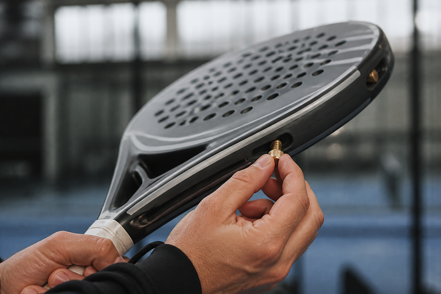 Detailopname van een aanpasbaar gewichtssysteem op een modern padelracket frame.