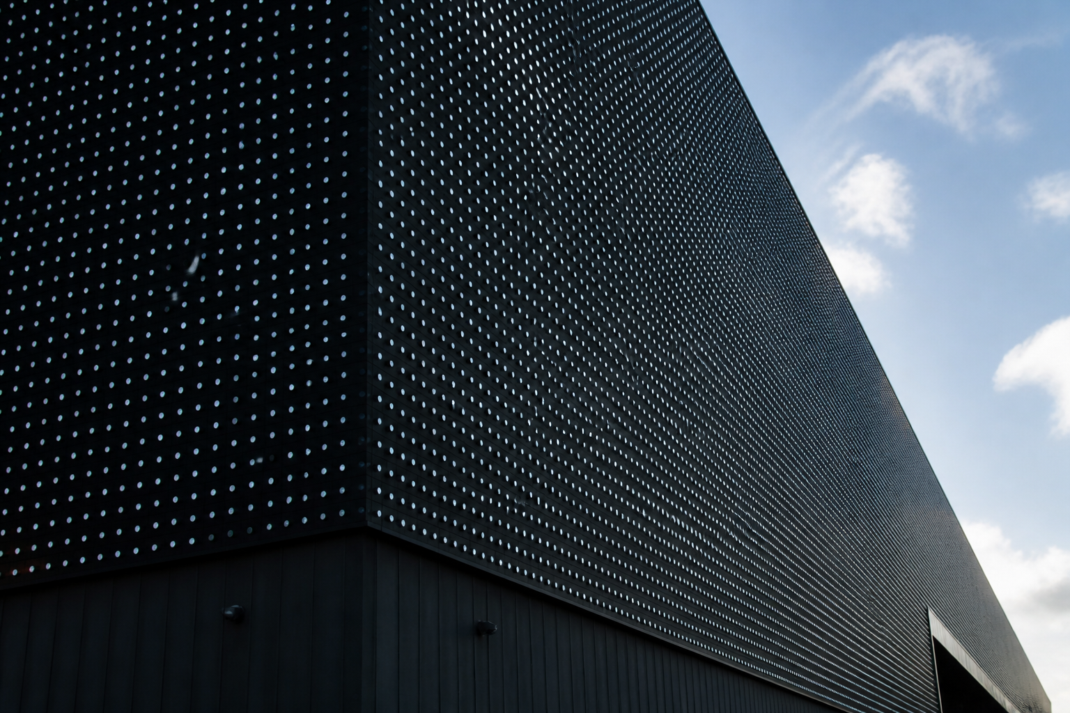 Detailopname van de moderne gevel van de Ziggo Dome in Amsterdam die de technologische uitstraling van de zaal benadrukt.