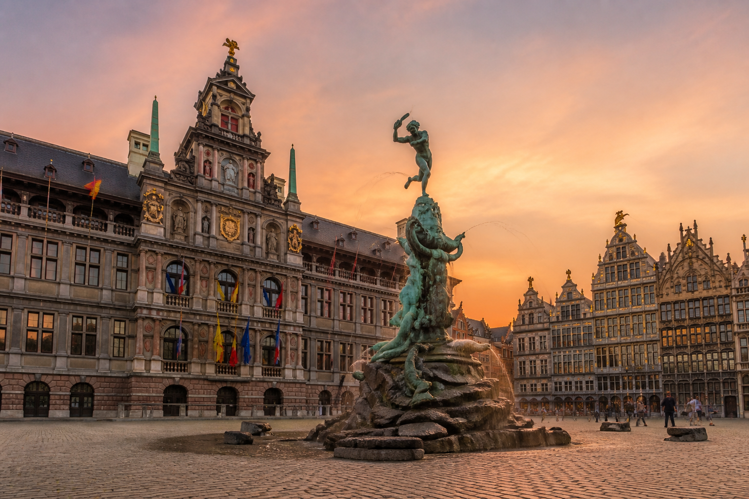 Wat te doen in Antwerpen: De historische Grote Markt met het Stadhuis en de Brabofontein tijdens zonsondergang.