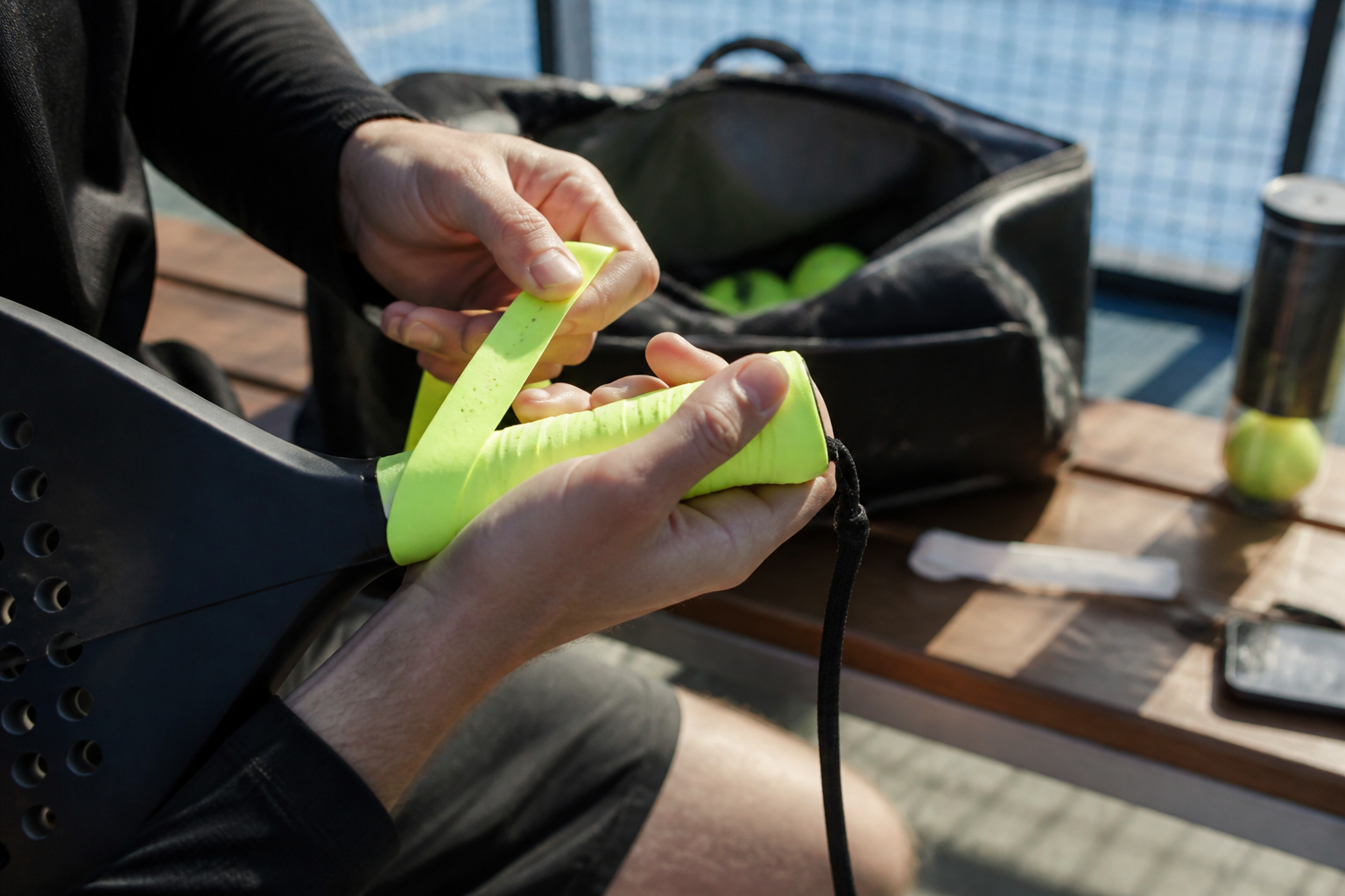 Het aanbrengen van een nieuwe overgrip op een padel racketgreep voor betere absorptie.