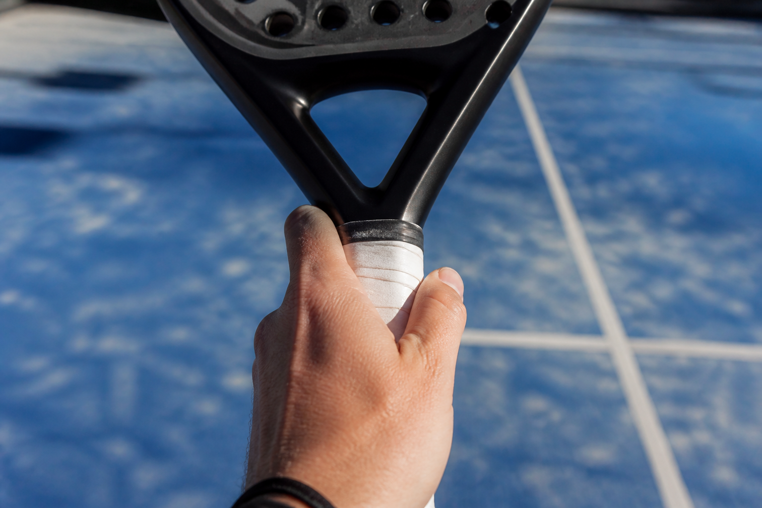 Close-up van de juiste continentale padel racketgreep op een handvat met witte overgrip.