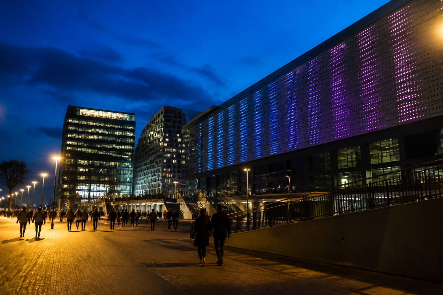 De verlichte Ziggo Dome en nabijgelegen hotels aan de Arena Boulevard in Amsterdam tijdens de avond.
